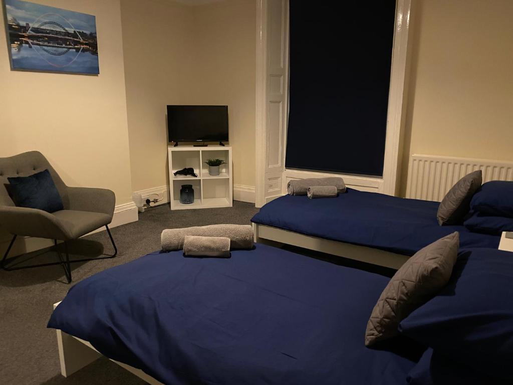 BlytheTown centre stay Northumberland FREE WIFI AND CLOSE TO BEACH的一间卧室配有两张床、一把椅子和电视
