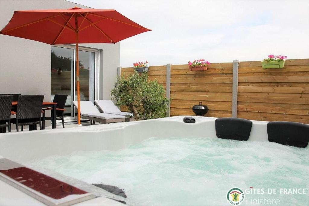 桑泰克Villa le Nid Des Dunes & Spa 2 gîtes écologiques的庭院内带遮阳伞的热水浴池