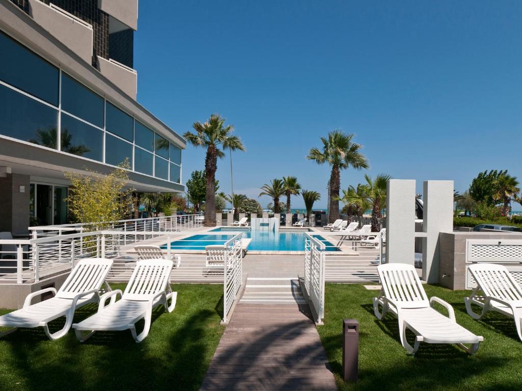 阿尔巴·阿德里亚蒂卡伊甸园酒店的一组白色躺椅,位于游泳池旁