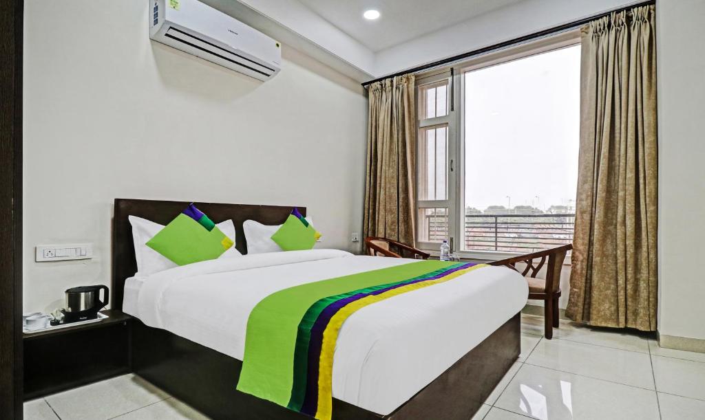 MohaliTreebo Kamron Regency Sector 80的一间卧室设有一张床和一个大窗户