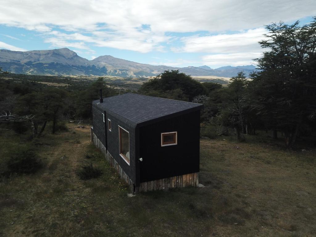 百内三塔Cabaña en Laguna Azul Patagonia Bagual的田间中的一个黑小房子