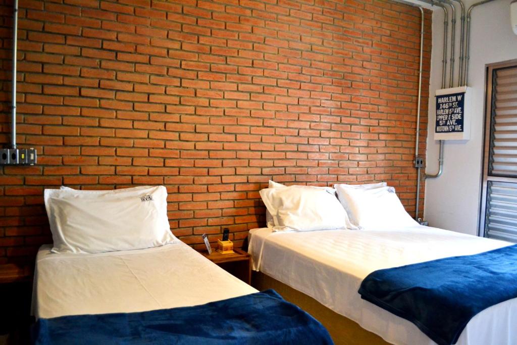 圣保罗Studio House Hotel的砖墙客房的两张床