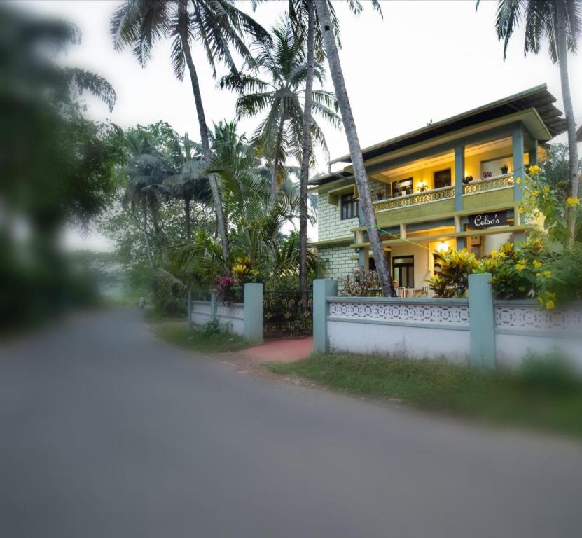 帕纳吉Celso's Home Stay的黄色房子,有白色的围栏和棕榈树