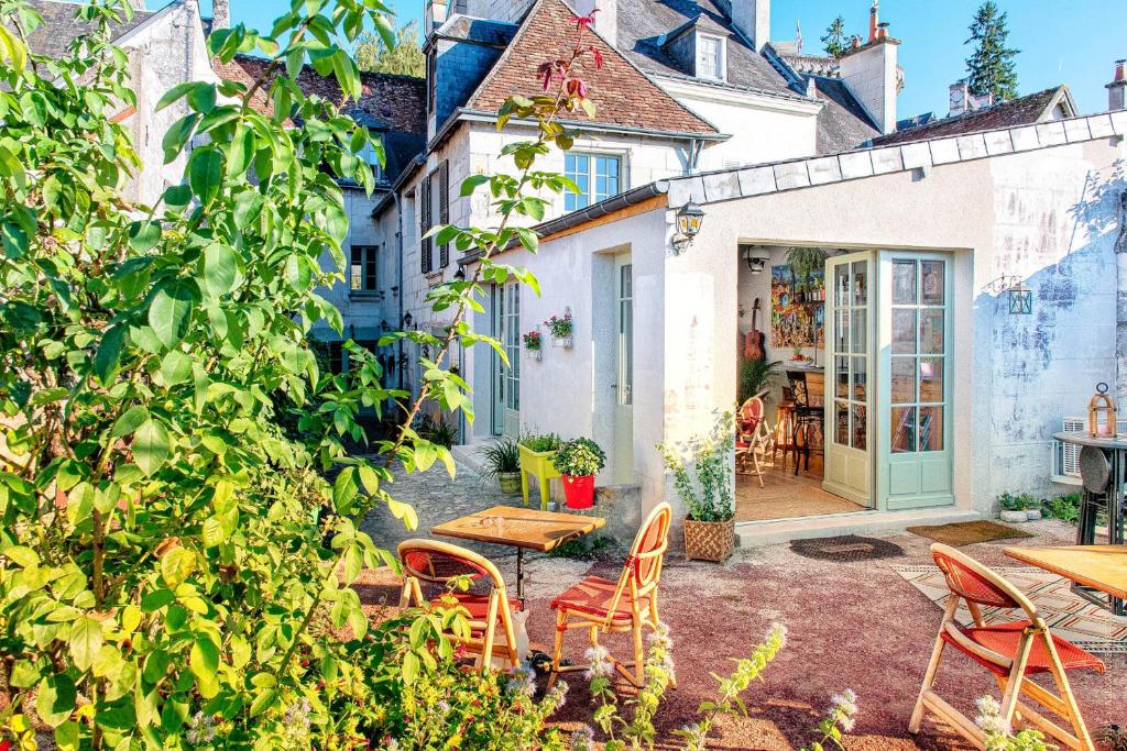 洛什La Little Maison的一个带桌椅的庭院和一座建筑