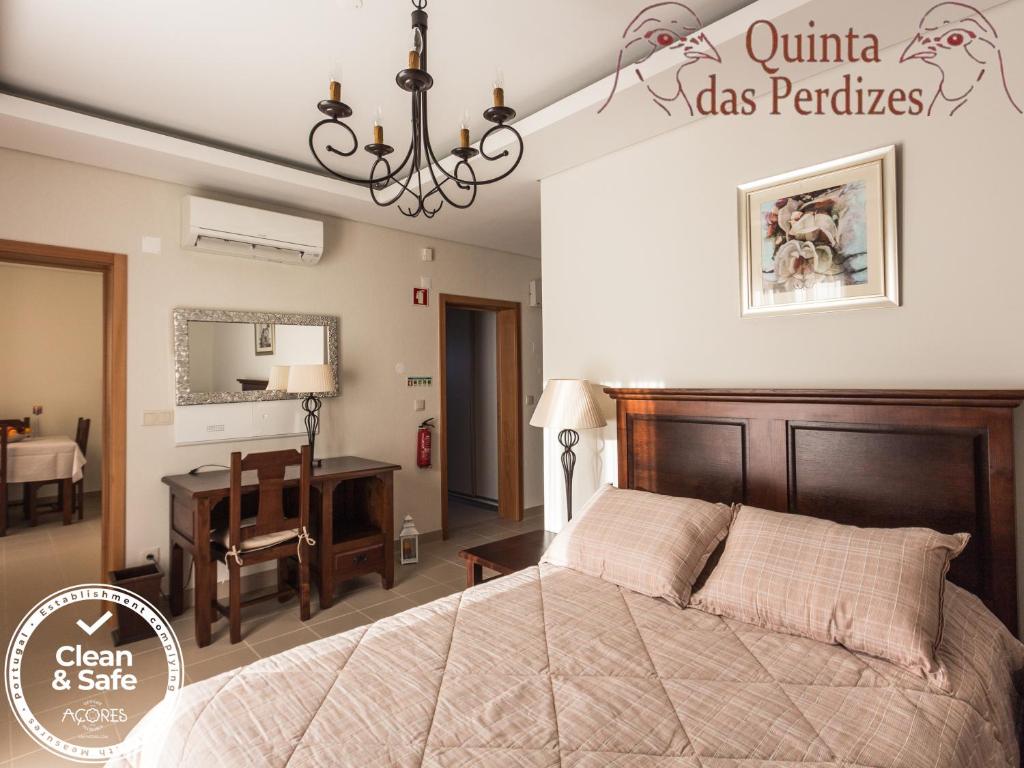 蓬塔德尔加达Quinta das Perdizes的一间卧室配有一张大床和一张书桌