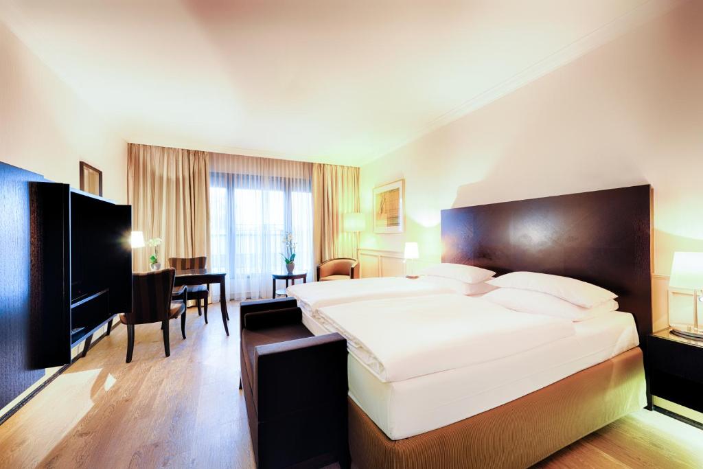 奥伊斯基兴Welcome Parkhotel Euskirchen的酒店客房设有一张大床和一张桌子。