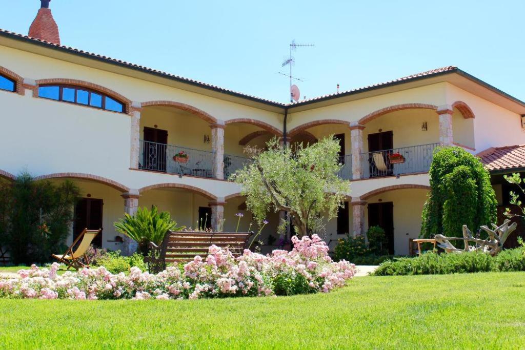 马萨马里蒂马Agriturismo Vecchio Imposto的一座大房子,带粉红色花的院子
