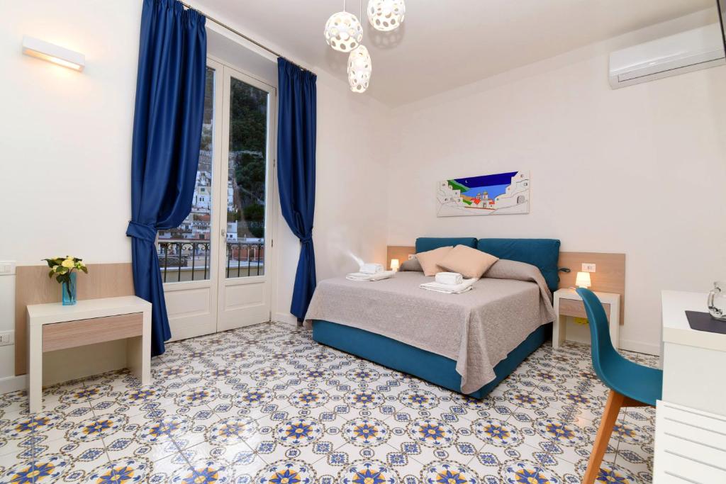 阿马尔菲Antica Residenza Amalfitana的一间卧室配有床、蓝色窗帘和窗户