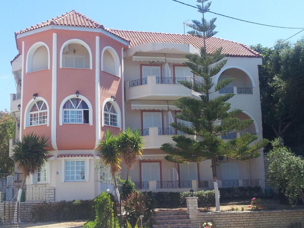 利贾Hotel Agios Thomas的前面有棵树的粉红色建筑