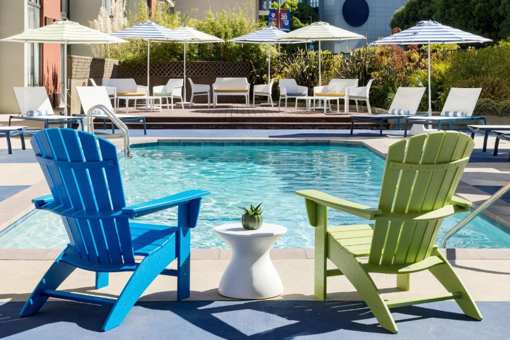 旧金山Hotel Caza Fisherman's Wharf的游泳池旁的两把蓝色和绿色椅子