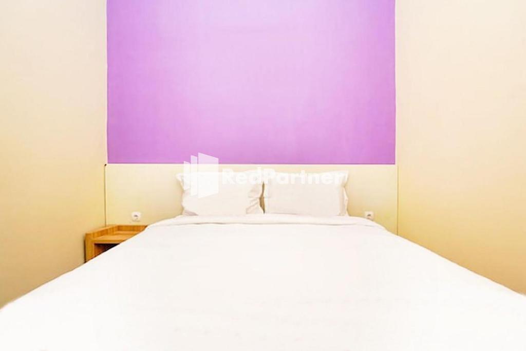 泗水Kupang Gunung Homestay Syariah near Islamic Center Surabaya Mitra RedDoorz的卧室配有白色的床和紫色墙壁
