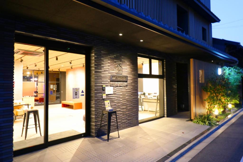 京都M's Hotel Sanjo Omiya的一座带玻璃门和庭院凳子的建筑