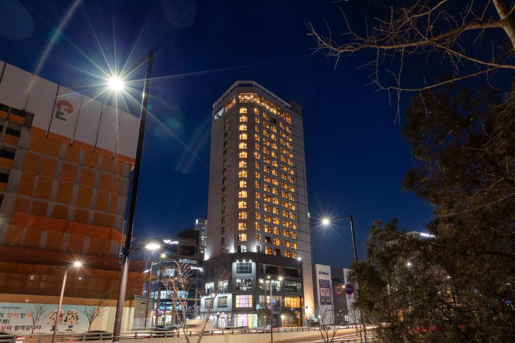 高阳市Urban-Est Hotel的一座高大的建筑,晚上有灯