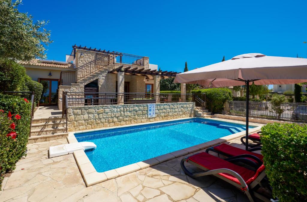 库克里亚3 bedroom Villa Madelini with private pool, Aphrodite Hills Resort的一个带两把椅子和遮阳伞的游泳池