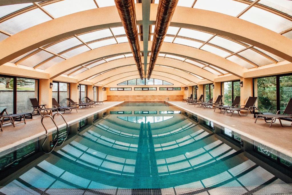 萨克德佐尔镇Teghenis Resort的一个带椅子和天花板的室内游泳池