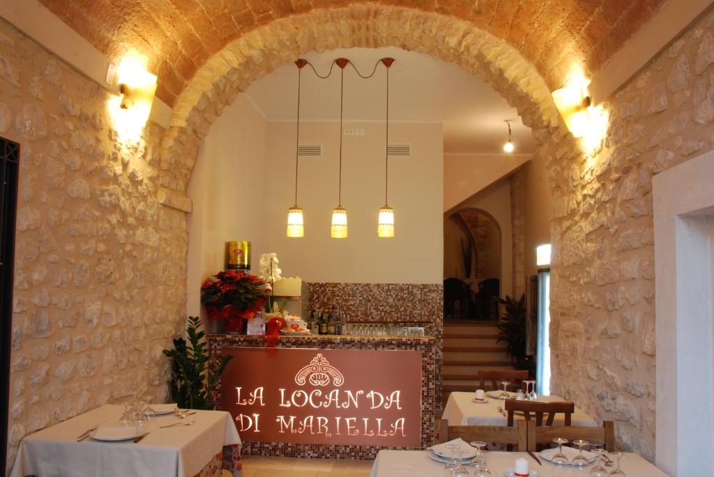 Poggio Picenze马利拉1950旅馆的餐厅设有白色桌子和带拱门的墙壁