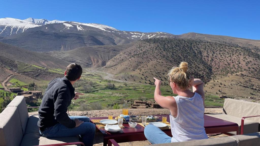 Zawyat OulmziTouda Ecolodge Atlas Mountains的坐在山顶上的男人和女人