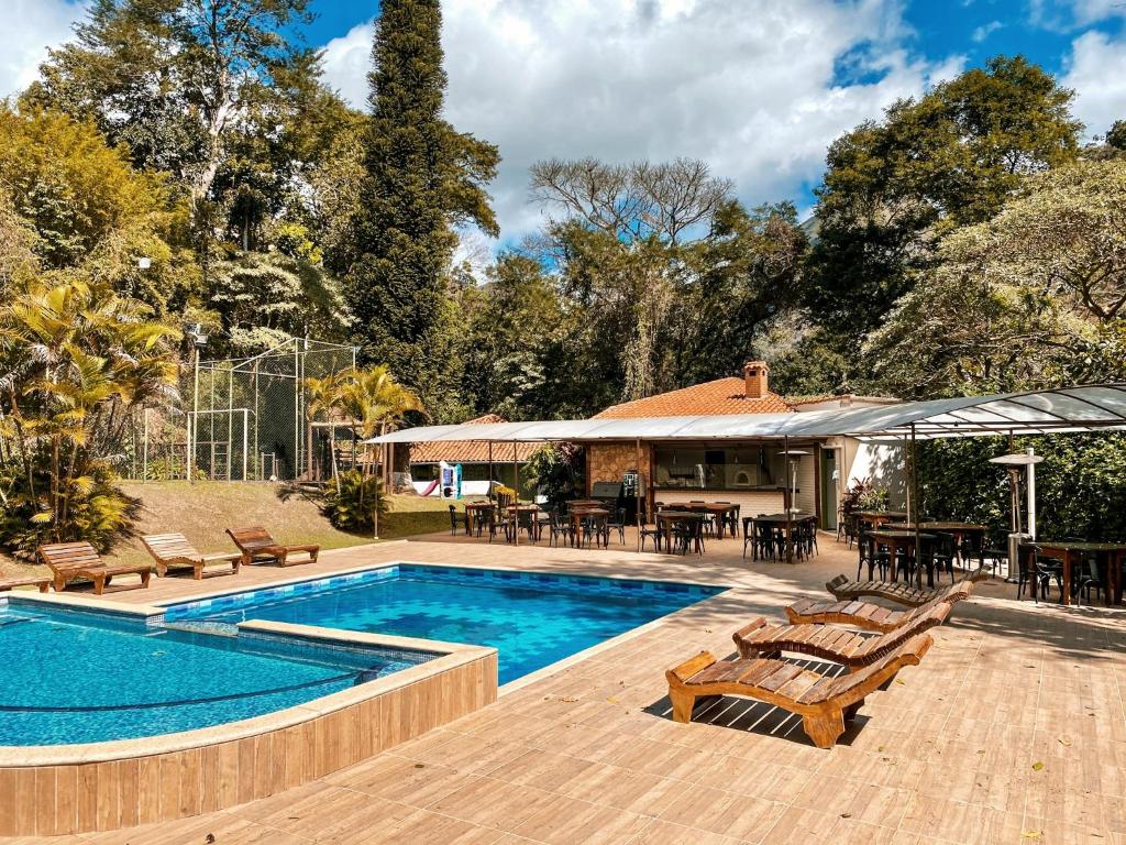 彼得罗波利斯Hotel Vila Bavária的一个带桌椅的游泳池以及一座房子