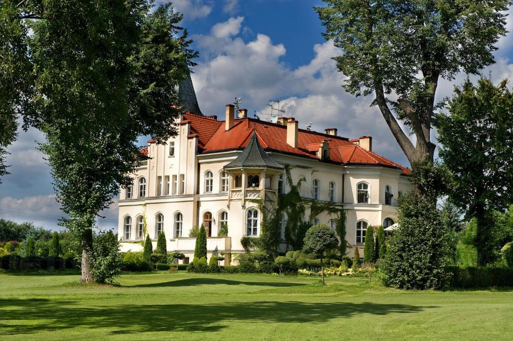 Oborniki ŚląskiePałac Brzeźno Spa & Golf的一座大型白色房屋,设有红色屋顶
