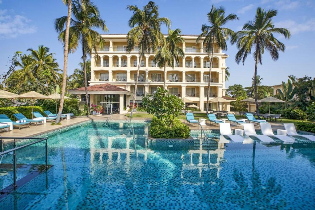 坎多林Holiday Inn Goa Candolim的一座拥有游泳池和棕榈树的酒店