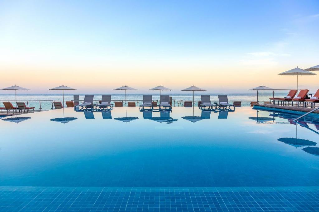 科苏梅尔科苏梅尔宫全包酒店的海滩上带椅子和遮阳伞的游泳池