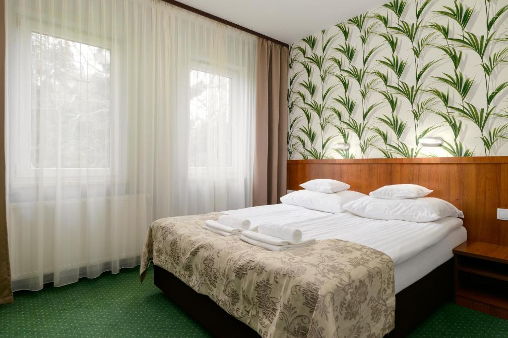 波兹南泽罗尼酒店的一间卧室设有一张带花卉墙壁的大床