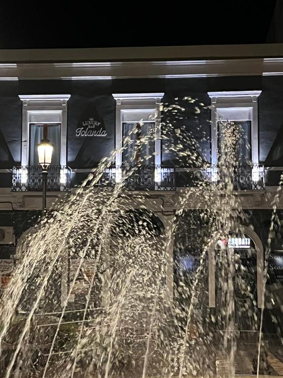 卡塔尼亚Luxury B&B Iolanda的夜间在建筑物前的喷泉