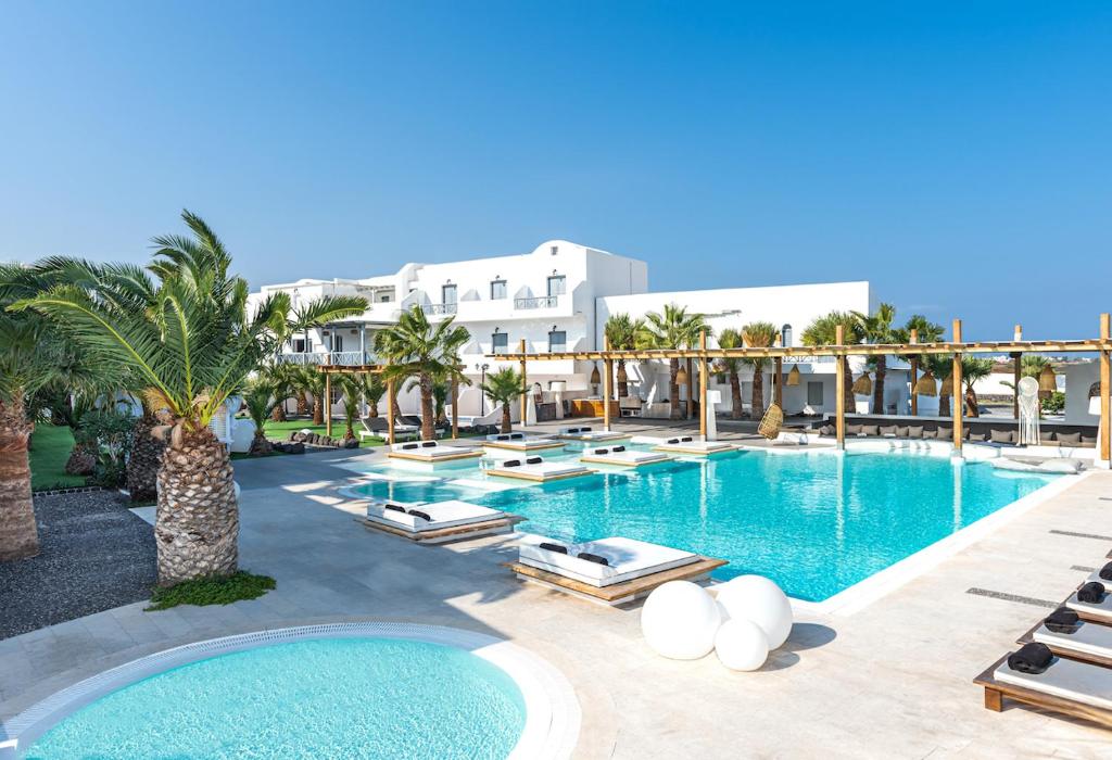 卡马利Smy Mediterranean White Santorini的一个带躺椅的大型游泳池,棕榈树