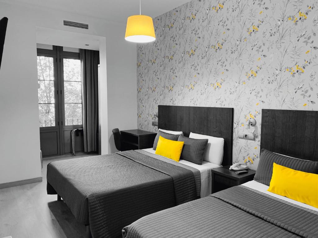 巴塞罗那Ciudad Condal Hostal - Paseo de Gracia的一间卧室配有两张带黄色枕头的床