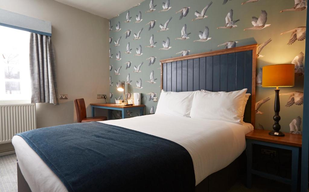 希钦Sun Hotel by Greene King Inns的卧室配有一张墙上鸟床