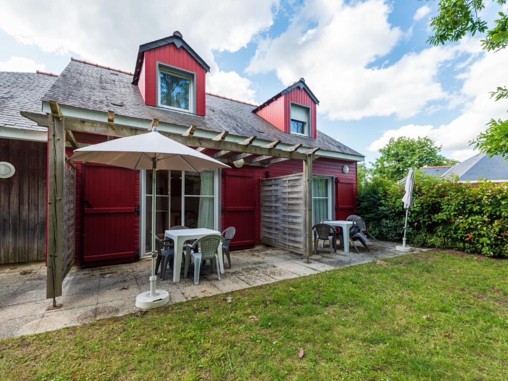 索米尔Holiday Home Cottage Confort 4 Pers- by Interhome的红色的房子,设有配有椅子和遮阳伞的庭院