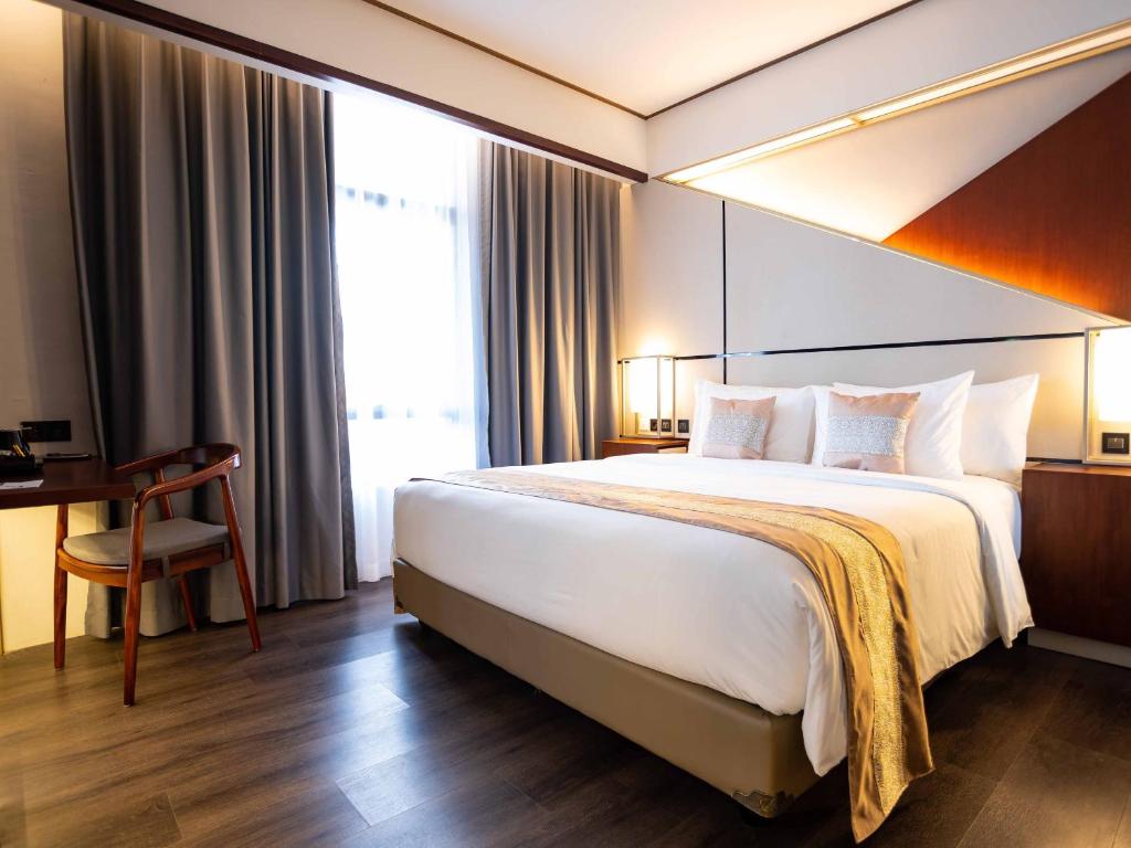 玛琅Rayz UMM Hotel Malang的酒店客房设有一张大床和一张书桌。