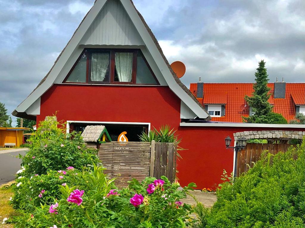 普鲁滕Ferienhaus Pruchten FDZ 201的一座红色的房子,屋顶尖顶,花朵