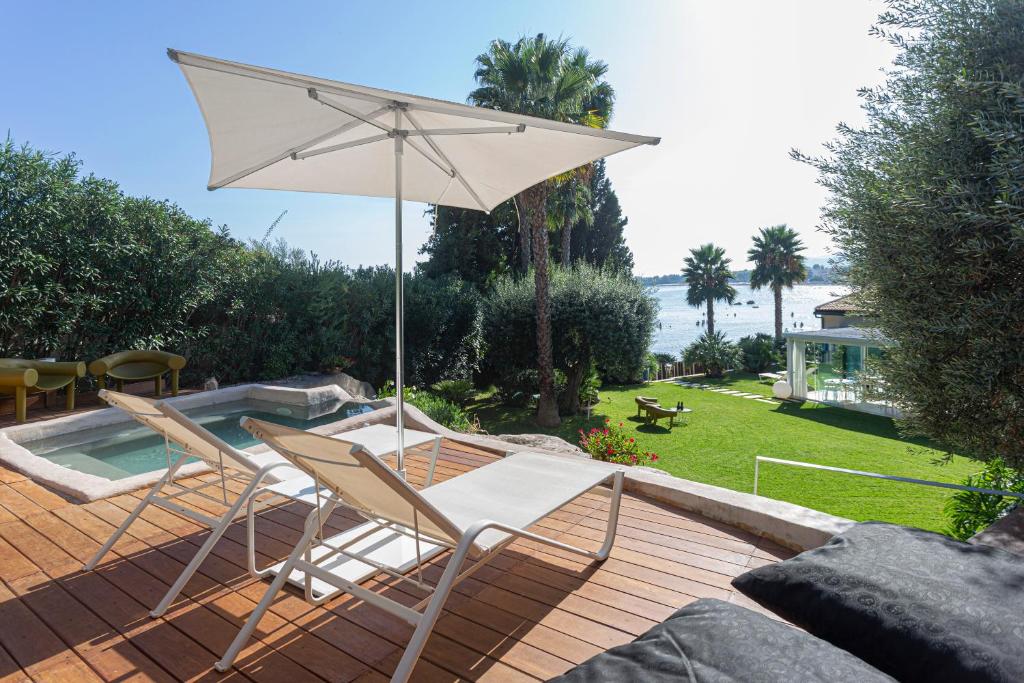 冯塔尼比安奇Calapetra Resort的庭院配有两把椅子和一把遮阳伞