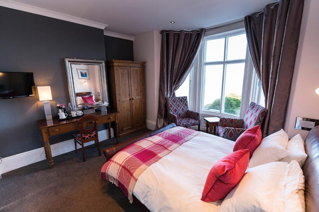 斯卡伯勒和里钠酒店的一间卧室配有一张带红色枕头的床和一扇窗户