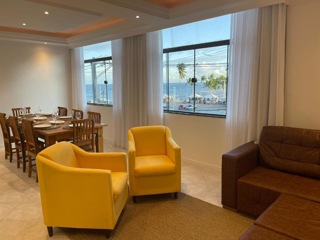 萨尔瓦多SALVADOR Ondina 3 quartos frente praia的一间带桌子和黄色椅子的用餐室