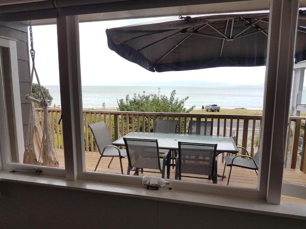 TapuCoromandel Tapu - Beachfront Escape的海滩景阳台配有桌椅