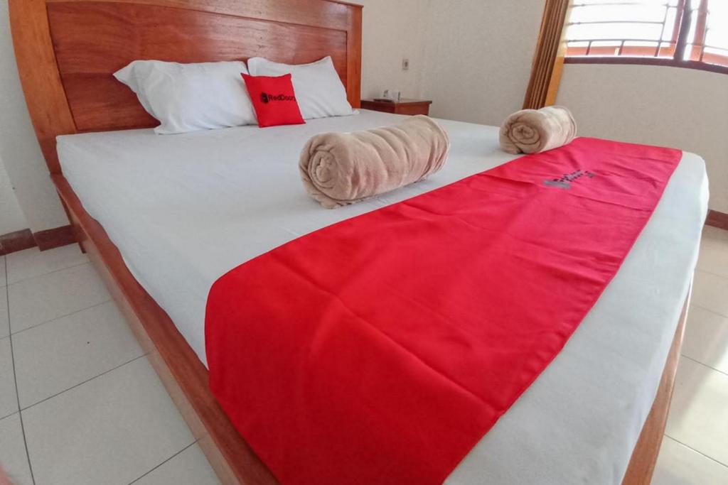 TobadiRedDoorz Syariah at Abemoch Kampkey的一间卧室配有一张床铺,床上铺有红色毯子