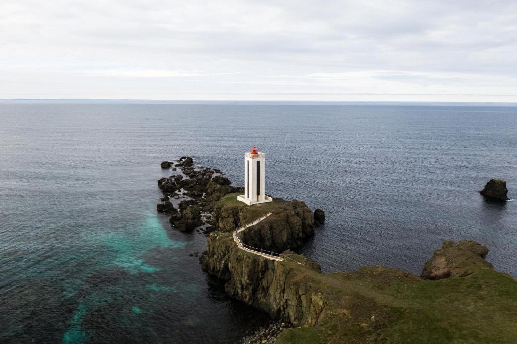 BakkafjörðurNorthEast Guesthouse的海洋中岩石岛上的灯塔