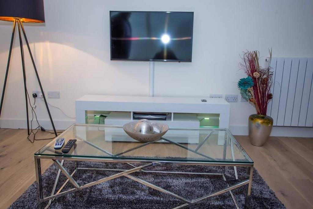 伦敦UNIQUE 2 BED APARTMENT的客厅配有玻璃桌和电视