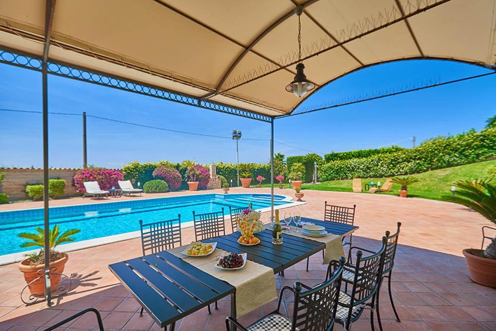 卡塔尼亚Villa Dinira的一个带桌椅的庭院和一个游泳池