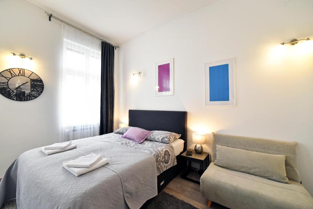 萨格勒布Deluxe Apartments Ria的一间卧室配有一张床、一把椅子和闹钟