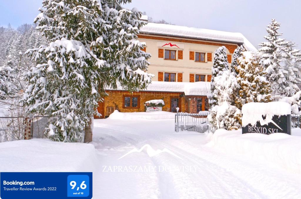 维斯瓦Beskid Ski Villa的一座房子,前面有树木,被雪覆盖着