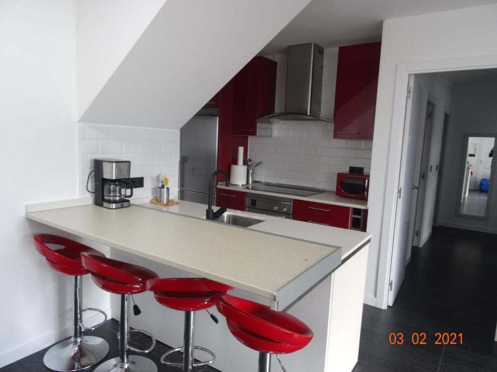 科巴罗Apartamentos Casa Mucha的厨房在柜台上设有红色的吧台凳