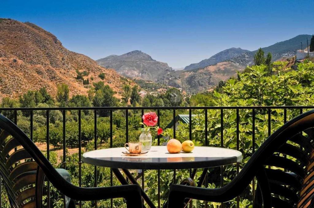 莫纳奇尔Casa Rural Las Huertas de Roque的山景阳台上摆放着水果和鲜花的桌子