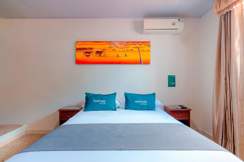 里奥阿查Ayenda Jimatta的一间卧室配有一张带两个蓝色枕头的床
