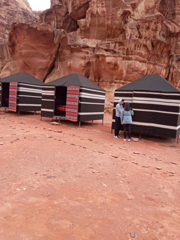 瓦迪拉姆Moon city camp的三人站在沙漠的黑白帐篷下
