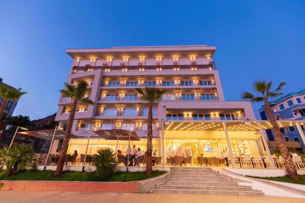 都拉斯AMR Hotel - Durres的一座楼前有棕榈树的酒店