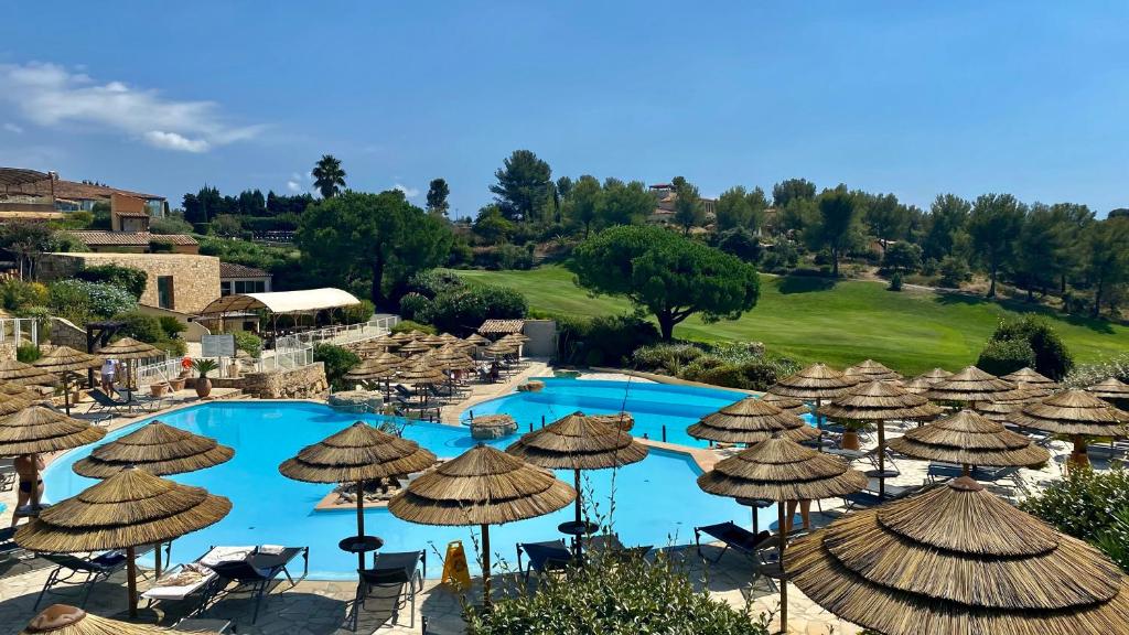 滨海圣西尔Hameau des amandiers-vue mer & golf的一座带遮阳伞和游泳池的度假村