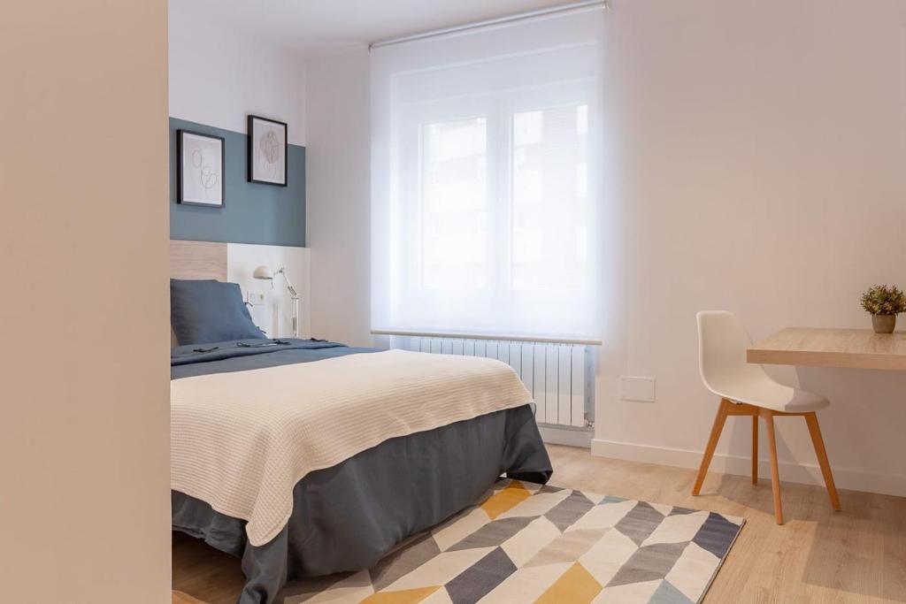 奥维多Room4You Oviedo by Asturias Holidays的一间卧室配有一张床、一张桌子和一把椅子
